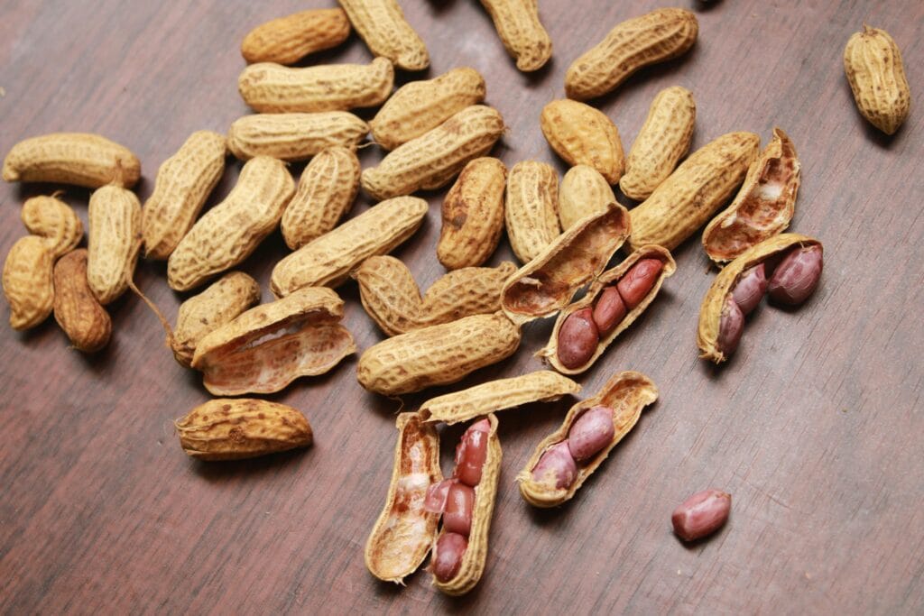A detailed view of peanuts in shells scattered on a wooden surface. Ideal for food themes.